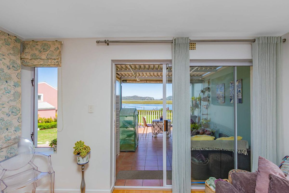 Interior living space featuring large sliding glass doors that open onto a covered patio with scenic water views.