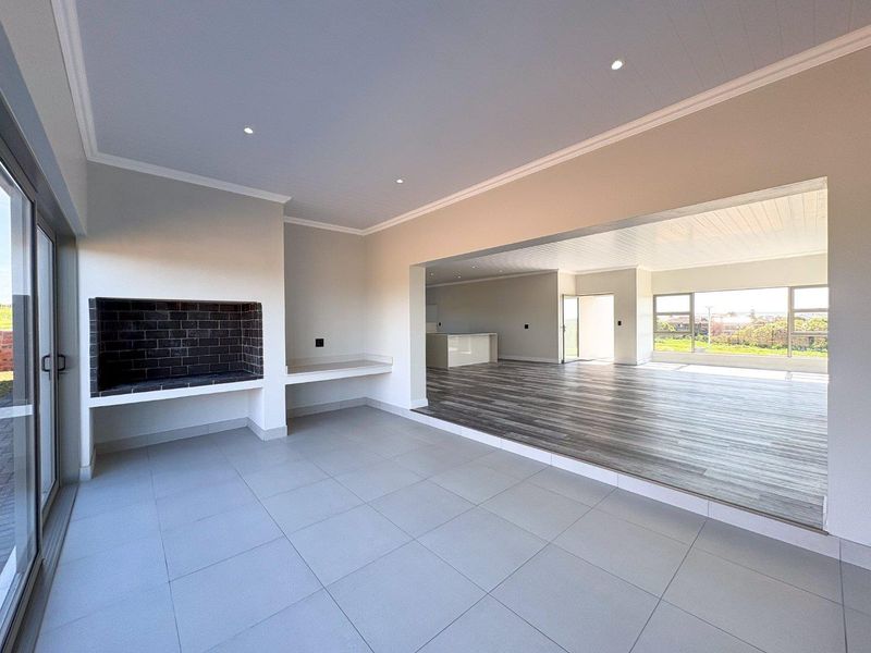 Spacious open-plan living area featuring a built-in fireplace, modern tiled and laminate flooring, recessed lighting, and large sliding doors leading to the exterior.