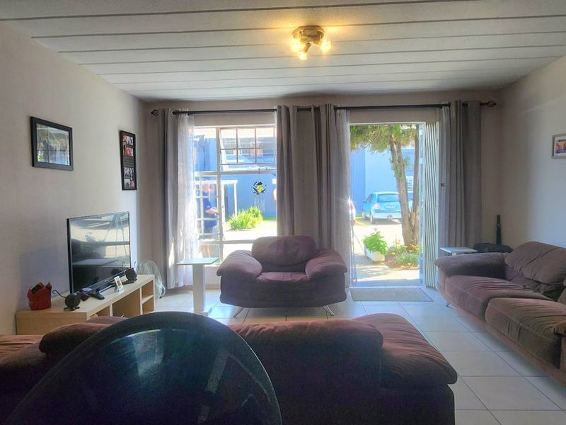 A comfortable living room featuring tiled flooring and a sliding glass door that provides direct access to the exterior.