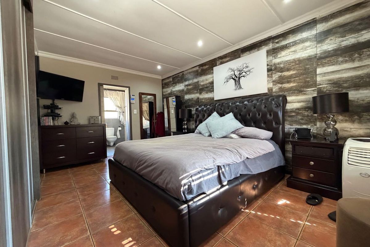 Spacious bedroom featuring tiled flooring, a decorative feature wall, recessed lighting, and direct access to an en-suite bathroom.