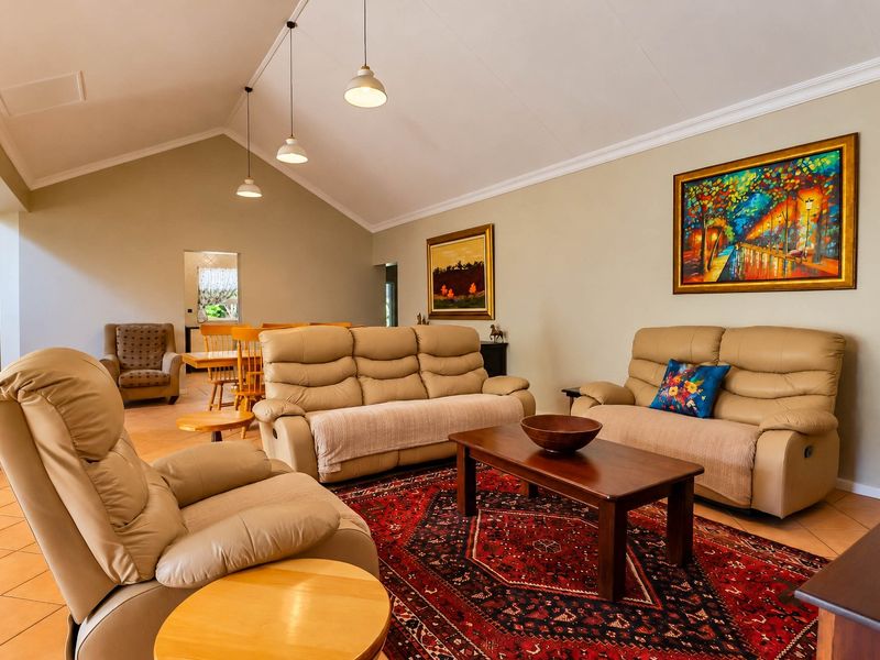 Spacious living room featuring a high vaulted ceiling, tiled flooring, and elegant pendant lighting, creating an open and inviting atmosphere.