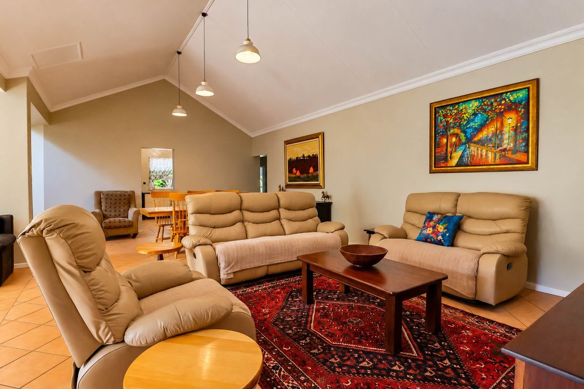 Spacious living room featuring a high vaulted ceiling, tiled flooring, and elegant pendant lighting, creating an open and inviting atmosphere.