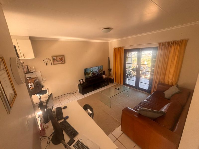 Open-plan living area featuring tiled floors and double glass doors leading to an outdoor space, providing a functional and versatile layout.