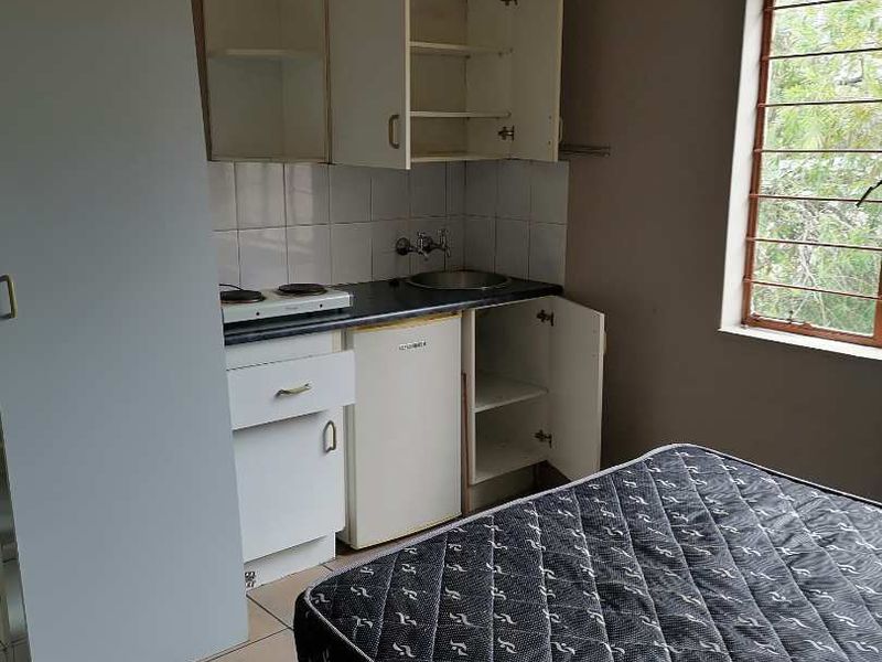 A compact kitchenette featuring basic built-in cabinetry, a sink, and an electric hob, suitable for a studio apartment layout.