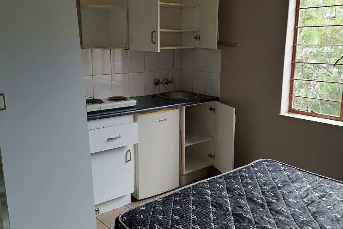 A compact kitchenette featuring basic built-in cabinetry, a sink, and an electric hob, suitable for a studio apartment layout.