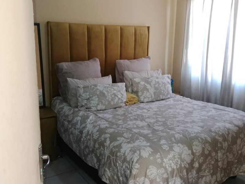 A functional bedroom featuring tiled flooring and neutral wall finishes, providing a comfortable and well-lit sleeping space.