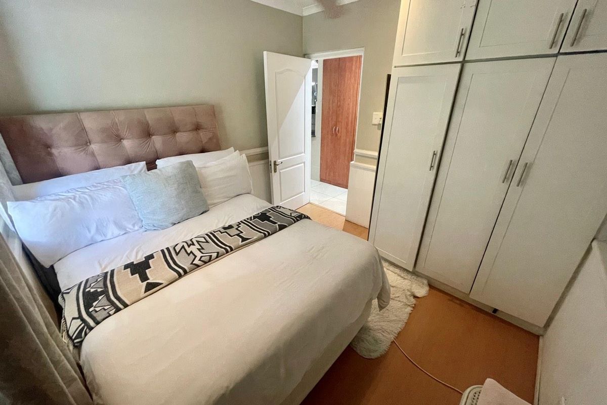 A bedroom featuring built-in floor-to-ceiling wardrobes, neutral wall tones, and access to an adjoining room.