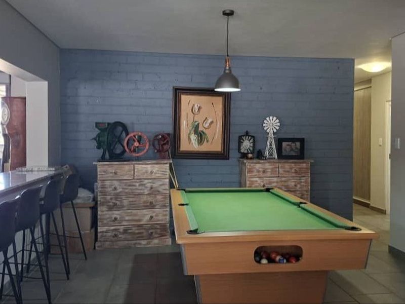 Spacious living area featuring a painted brick accent wall, tiled flooring, and a built-in breakfast bar, offering a versatile space for entertainment.