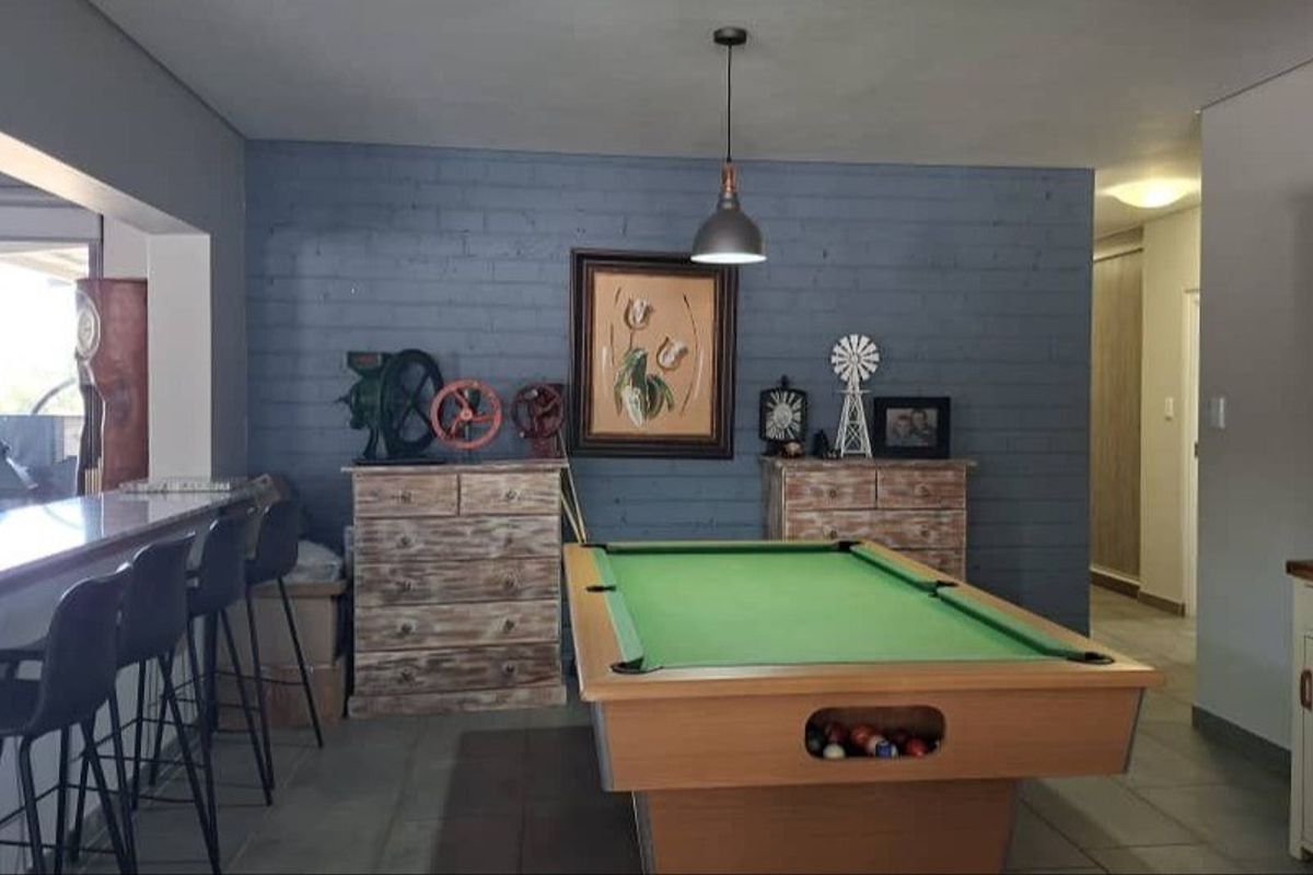 Spacious living area featuring a painted brick accent wall, tiled flooring, and a built-in breakfast bar, offering a versatile space for entertainment.