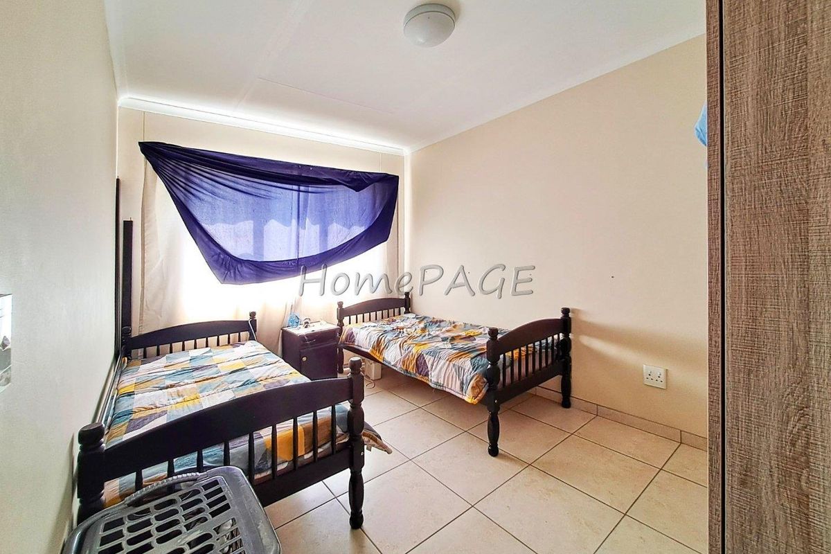 A bedroom featuring tiled flooring, built-in cupboard space, and a window with natural light.