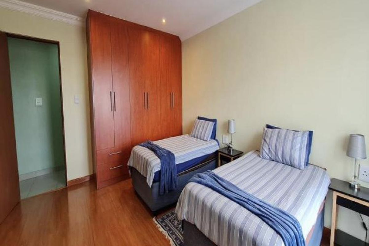 A bedroom featuring built-in wooden cabinetry and laminate flooring, with access to an adjacent room.