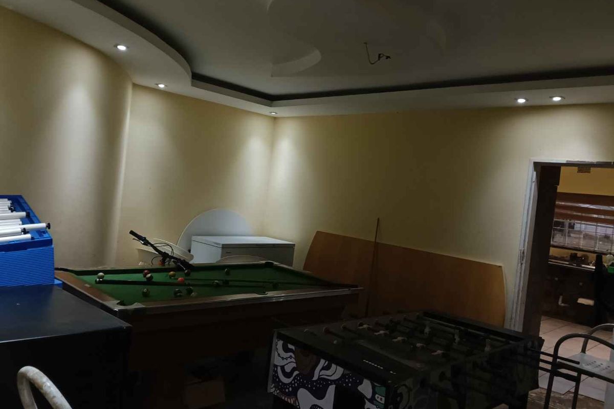 A spacious living area featuring recessed ceiling lighting, coved ceiling details, and tiled flooring, currently utilized as a recreational space.