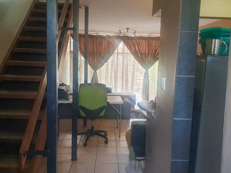 Open plan living area featuring a wooden staircase, tiled flooring, and access to a patio through a sliding door.