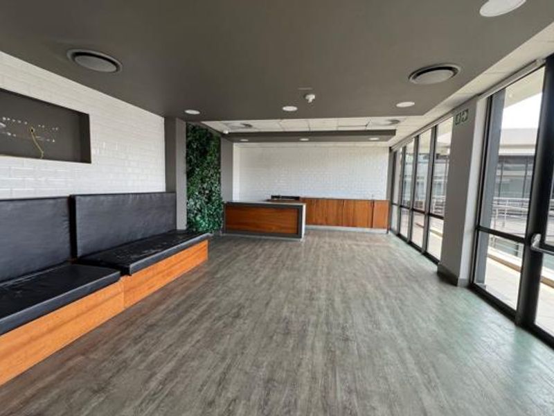 Modern office space featuring built-in bench seating, wooden cabinetry, subway tile accents, and large windows providing ample natural light.