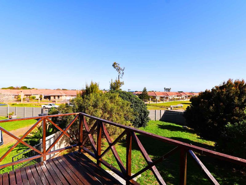 Elevated wooden balcony overlooking a residential garden and surrounding neighborhood.