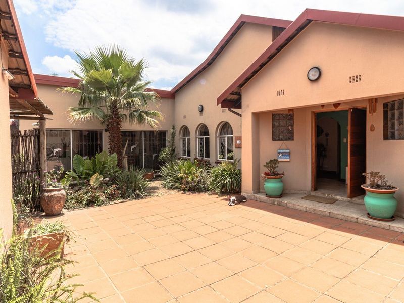 A spacious rear courtyard featuring tiled flooring, arched windows, and access to the main living areas through sliding glass doors.