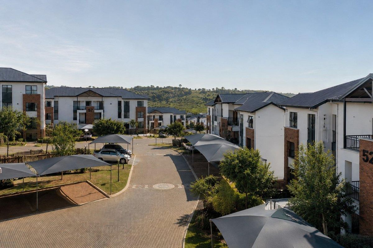 An elevated view of the apartment complex grounds, featuring paved driveways, designated shade cloth parking bays, and well-maintained residential building exteriors.