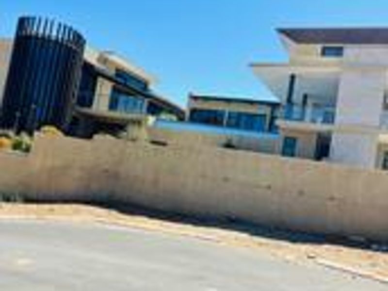 Street view showing the exterior facade of modern residential properties with balconies and a boundary wall.