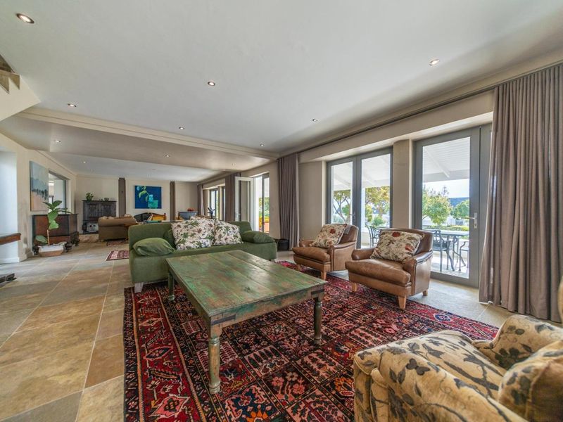 Spacious open-plan living area featuring stone flooring, recessed lighting, and large glass doors providing seamless access to the outdoor patio area.