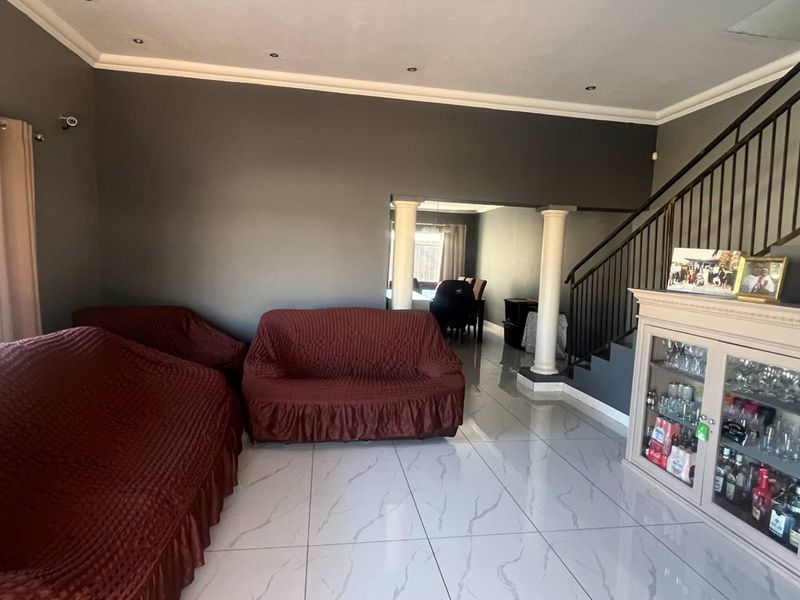 Spacious living area featuring polished marble-look floor tiles, a staircase with metal balustrade, and recessed ceiling lighting.
