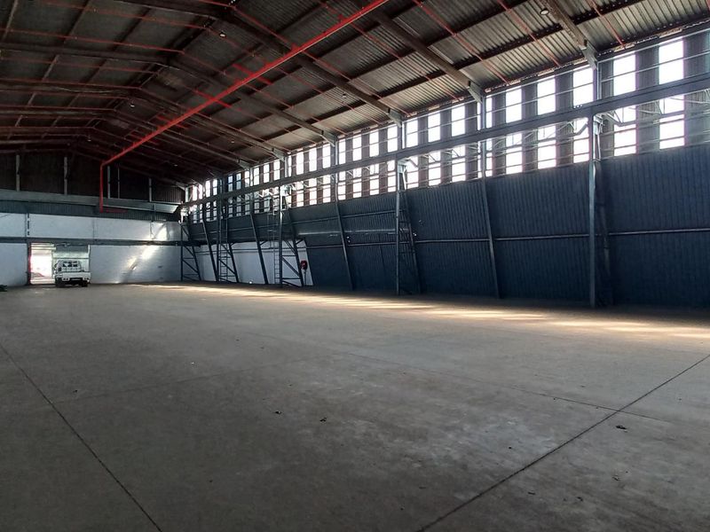 Spacious industrial warehouse featuring high ceilings, concrete flooring, steel structural framing, and ample natural light through high-level clerestory windows.