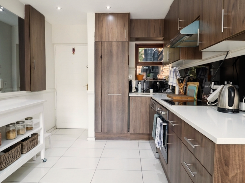 Modern kitchen featuring dark wood cabinetry, white quartz countertops, integrated appliances, and tiled flooring with recessed lighting.