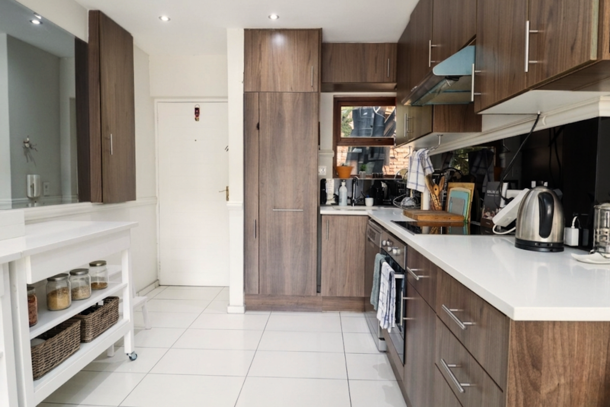 Modern kitchen featuring dark wood cabinetry, white quartz countertops, integrated appliances, and tiled flooring with recessed lighting.