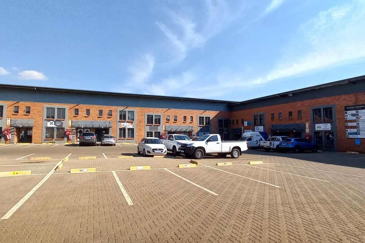 Exterior view of a modern industrial business park featuring brick facade, paved parking area, and multiple commercial unit entrances.
