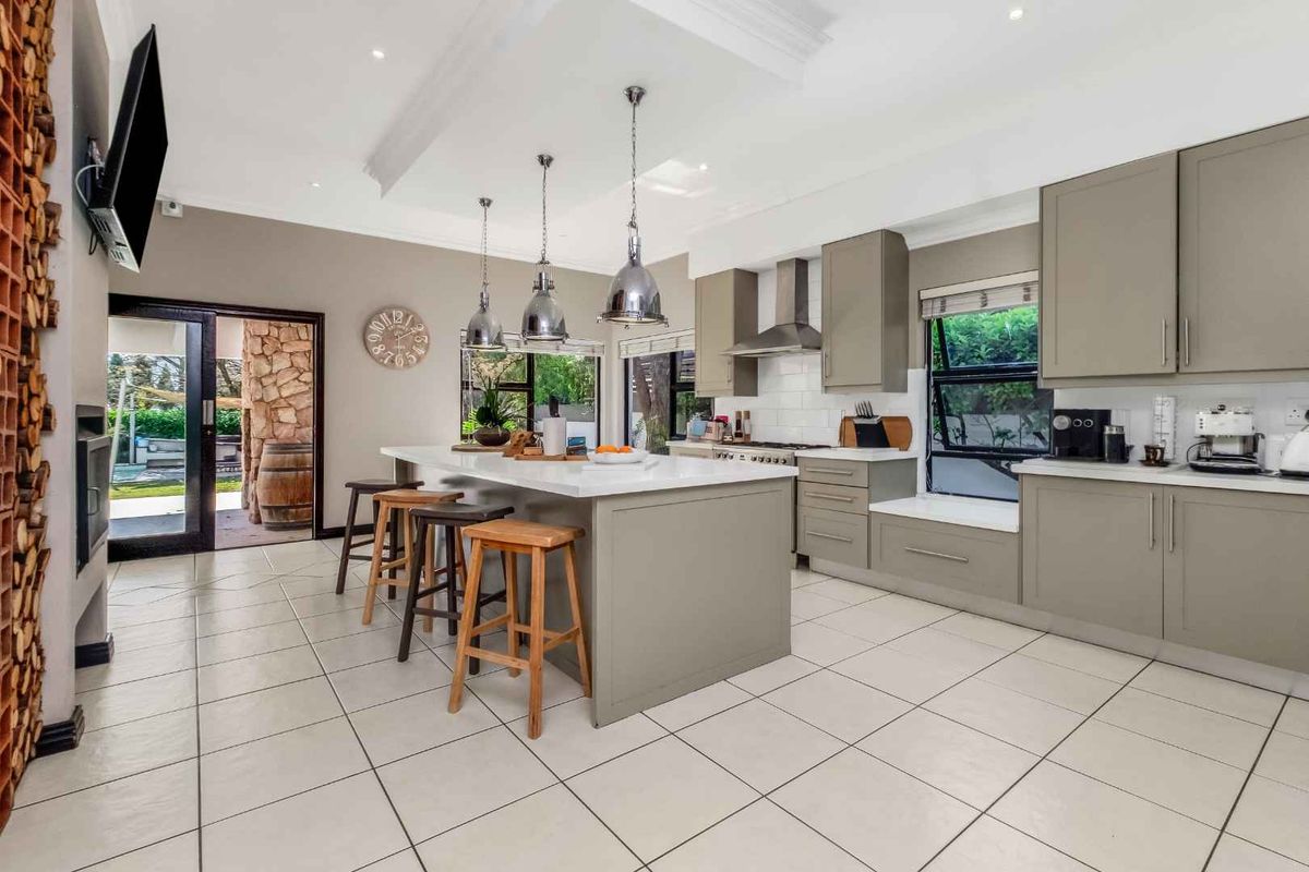 Modern kitchen featuring a large central island with quartz countertops, sleek cabinetry, stainless steel appliances, and direct access to an outdoor patio area.