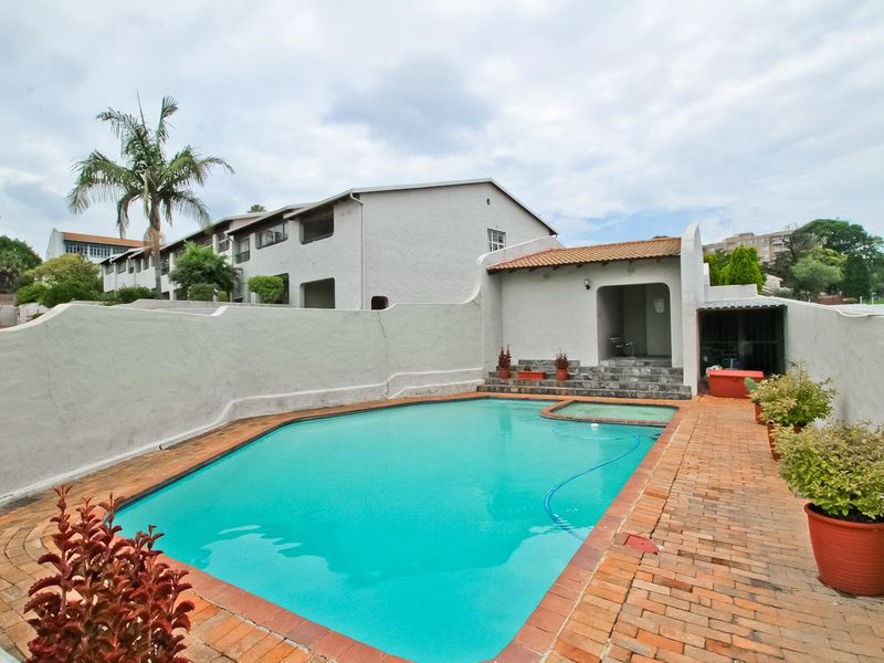 Outdoor pool area featuring a swimming pool, brick paved surround, and a small covered structure with built-in steps.