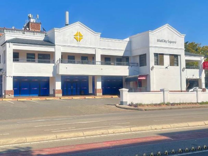 Front elevation of MidCity Square, a multi-level commercial building featuring a paved parking area and balcony access.