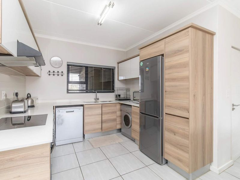 Modern kitchen featuring light wood-grain cabinetry, white countertops, tiled flooring, and integrated appliance spaces, offering a clean and functional culinary environment.