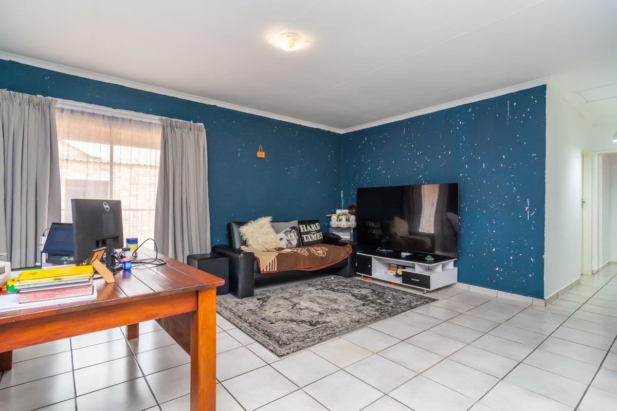 A living room featuring tiled flooring, a sliding glass door with curtains, and a prominent dark blue feature wall.