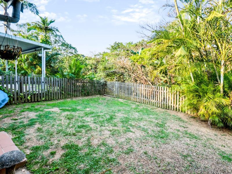 A private rear garden featuring a lawn area, established perimeter landscaping, and a covered patio space.