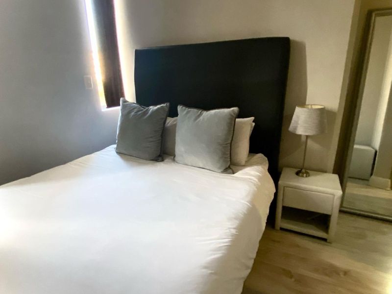 A cozy bedroom featuring light-toned laminate flooring and a built-in cupboard, providing a clean and functional living space.