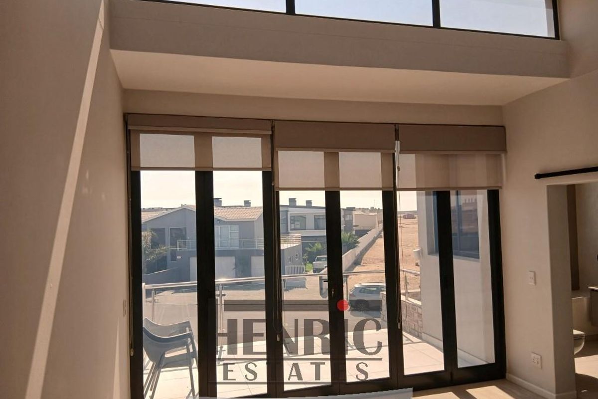 Bright and spacious living area featuring high ceilings, clerestory windows, and large sliding doors that open to an outdoor balcony.