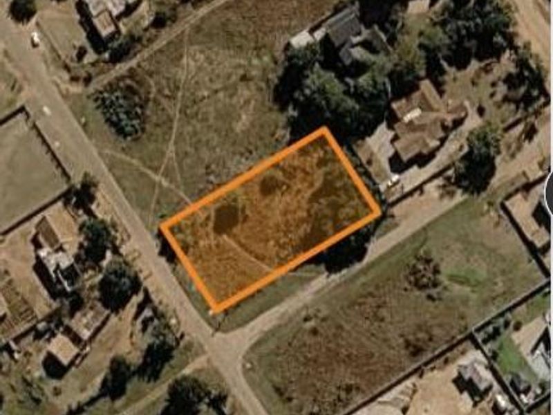An aerial view of a vacant residential plot highlighted with an orange boundary, situated within an established neighborhood.