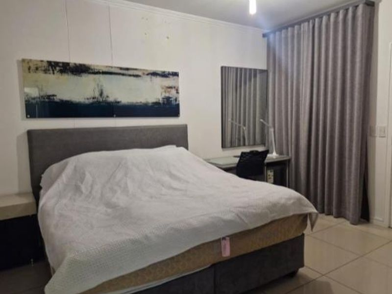 A well-maintained bedroom featuring neutral tiled flooring and full-length curtains, providing a clean and functional living space.