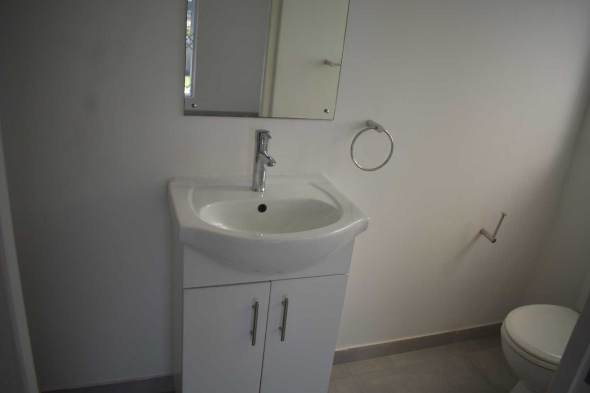 A clean and functional bathroom featuring a modern vanity with a basin, a wall-mounted mirror, and a standard toilet.
