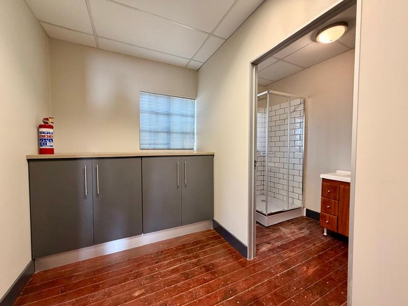 A functional bathroom area featuring built-in grey cabinetry, a shower enclosure with subway tiling, and a wooden vanity unit with a sink.