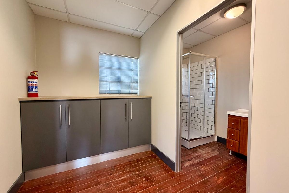 A functional bathroom area featuring built-in grey cabinetry, a shower enclosure with subway tiling, and a wooden vanity unit with a sink.