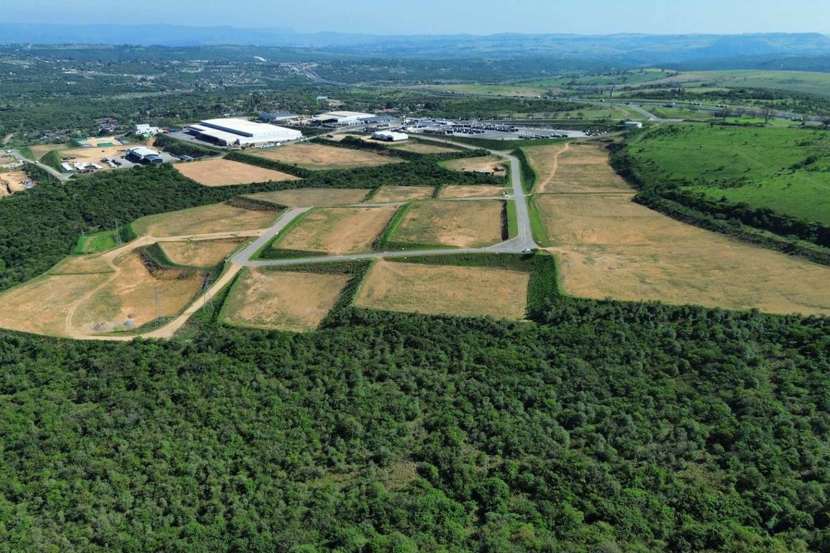 Aerial view of a large industrial development site featuring cleared land plots, paved access roads, and surrounding natural landscape.