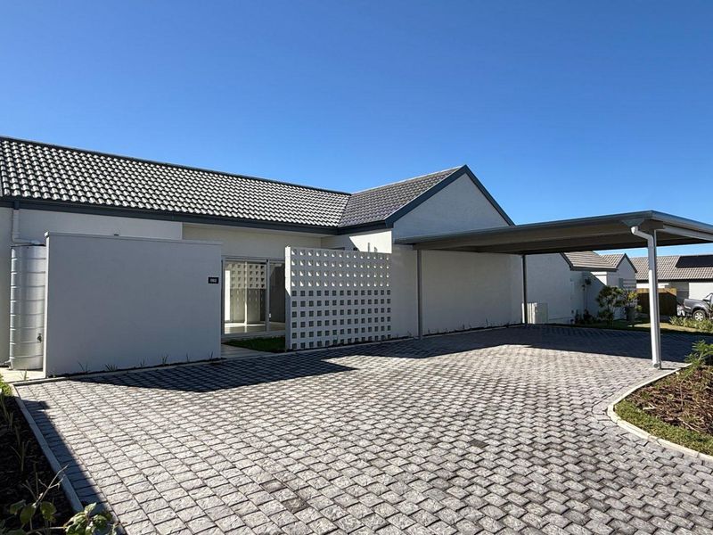 Front exterior view of a modern house featuring a paved driveway, carport, and decorative breeze block screen wall.