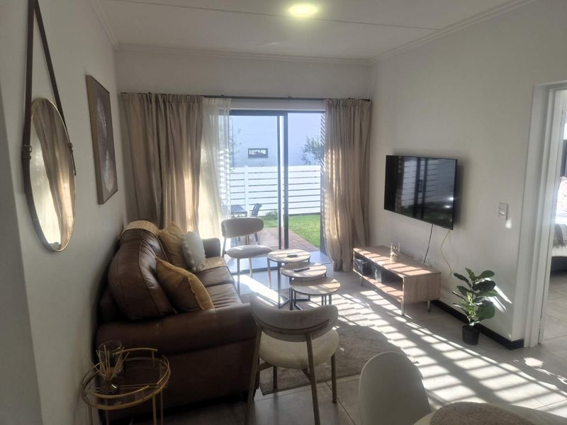 A bright living room featuring tiled flooring and a sliding glass door that provides direct access to an outdoor patio area.