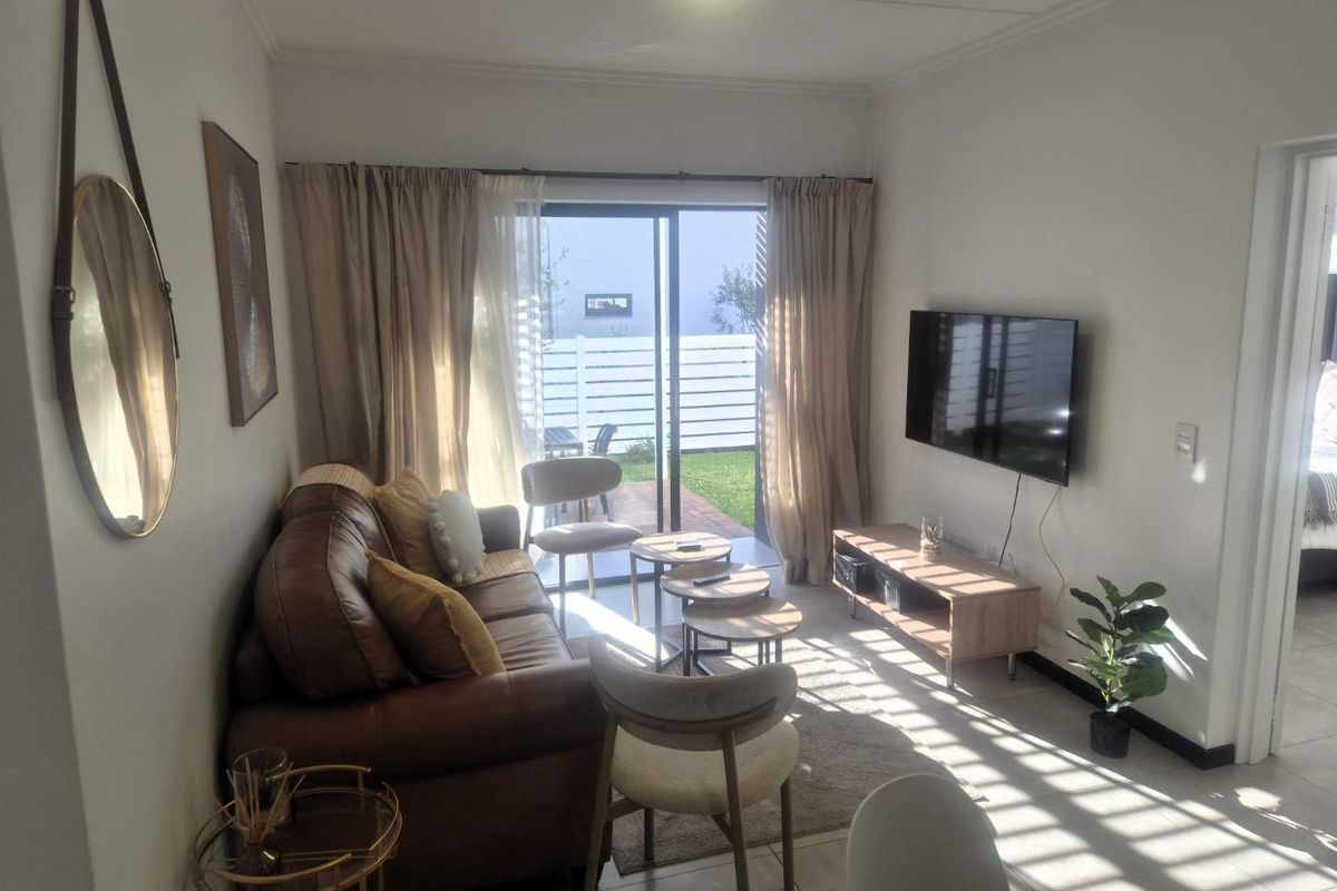 A bright living room featuring tiled flooring and a sliding glass door that provides direct access to an outdoor patio area.