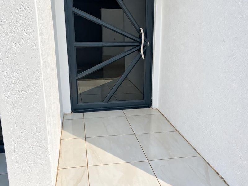 A clean and modern entrance featuring a contemporary glass and metal front door with polished porcelain floor tiles.