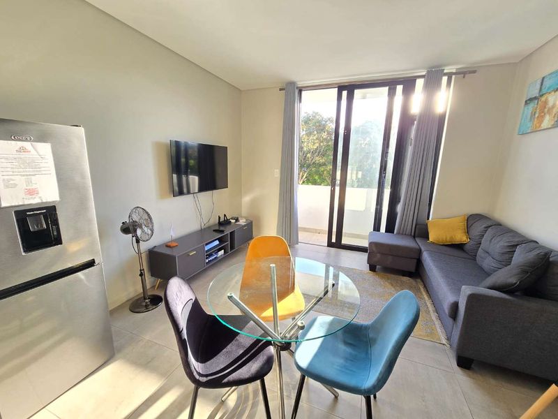 An open-plan living and dining area featuring tiled flooring and large sliding glass doors that provide access to an outdoor balcony.