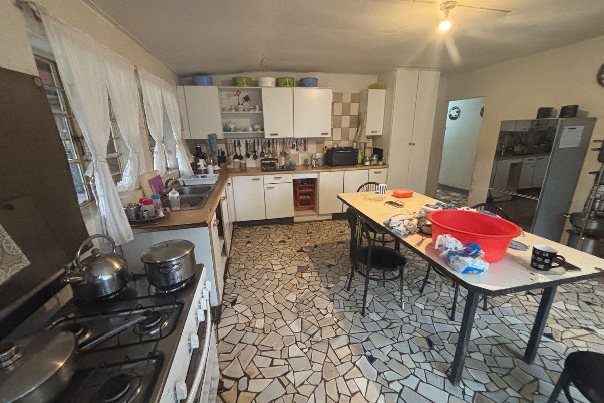 A dated kitchen featuring original cabinetry, a gas stove, and unique mosaic-style flooring, offering a functional space with potential for modernization.
