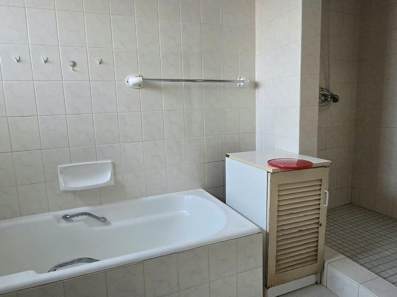A functional bathroom featuring a built-in bathtub, a separate walk-in shower, and full-height wall tiling.