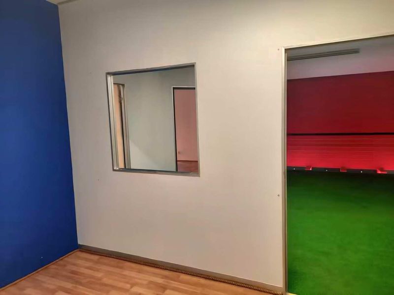 An empty office space featuring laminate flooring, a blue accent wall, and an internal window looking into an adjacent room.